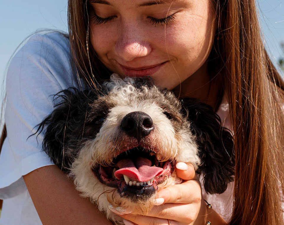 Young woman smiling and holding a happy, panting dog.